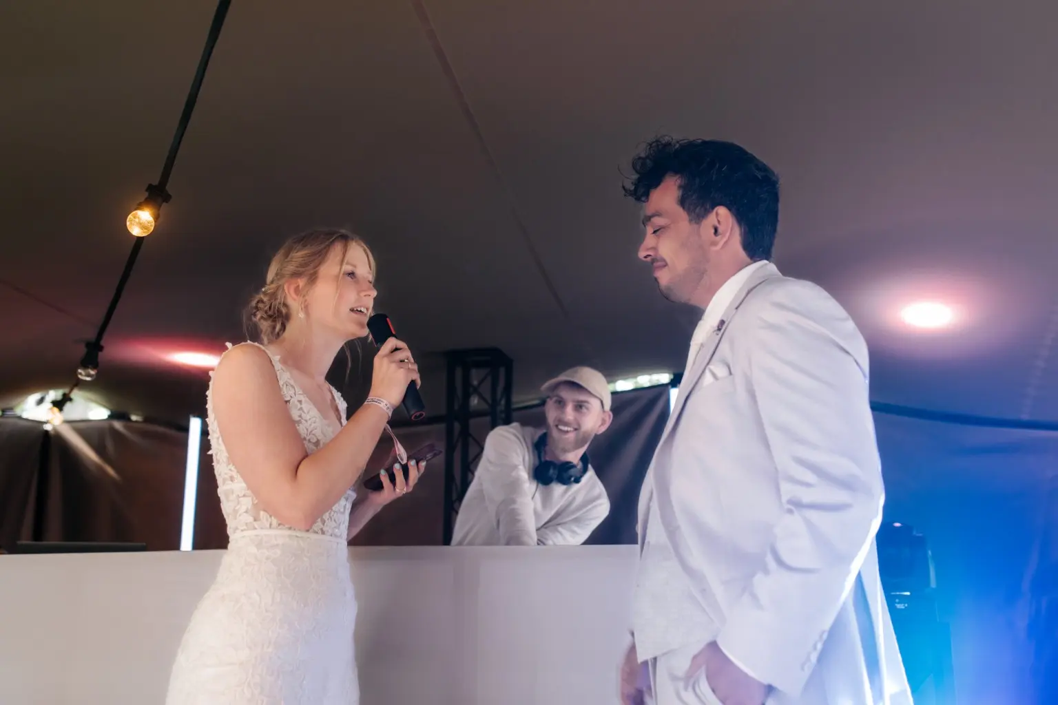 Het bruidspaar bij de witte DJ-booth met Coenakis tijdens de bruiloft van W&D